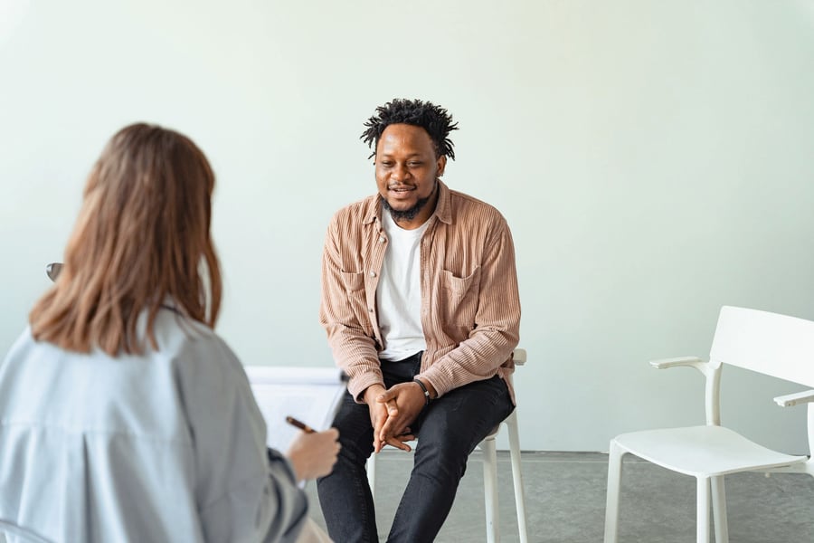 Two people in conversation in a bright, quiet consulting room during a counselling session.