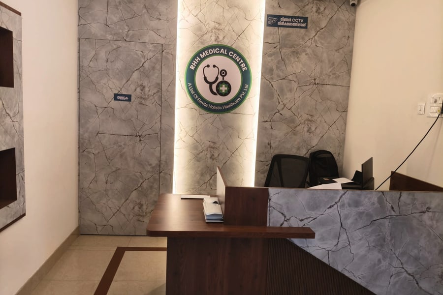 The reception area: the RHH Medical Centre emblem lit against a marble wall, with a wooden reception desk in front of it.